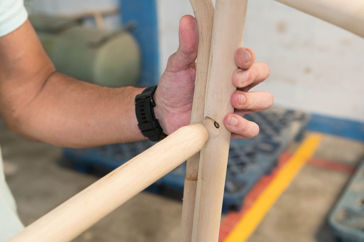 Hands piecing together the joints of a rattan frame.