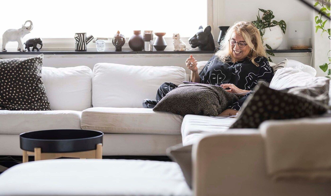 Cecilia sits on the sofa, drawing and smiling.