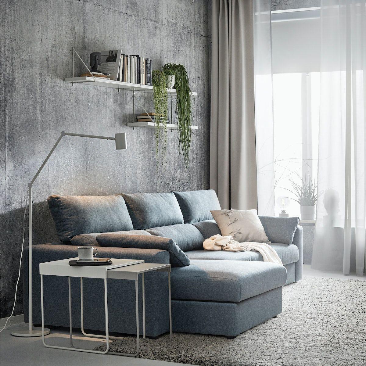 A blue ESKILSTUNA sofa in a living room with tables next to it.