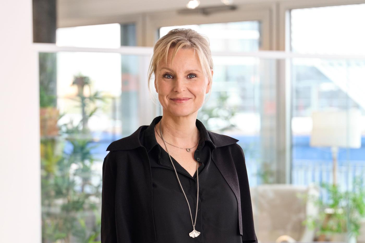 Portrait of Elisabeth Munck af Rosenschold standing in an office environment, wearing a black shirt.