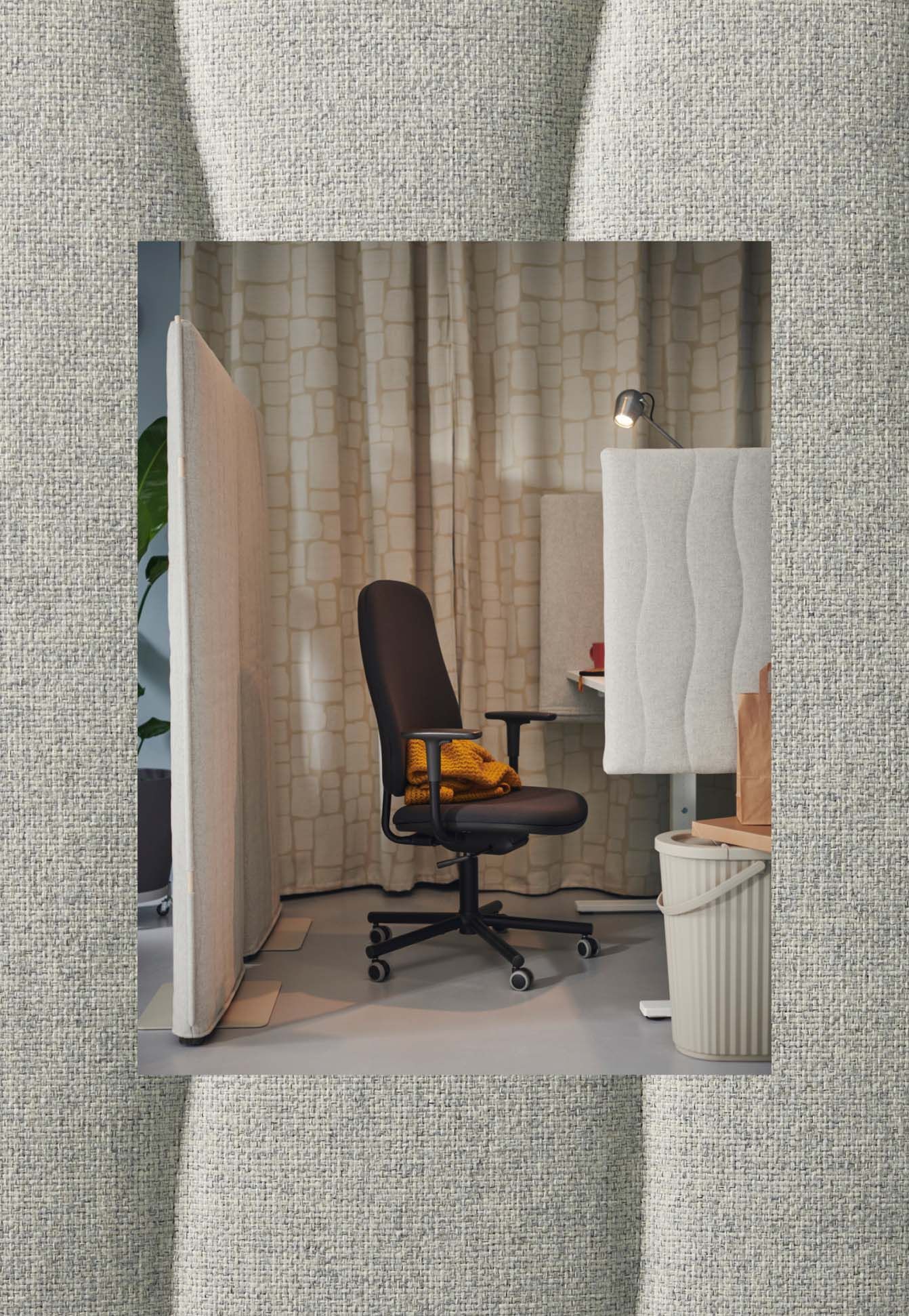 A MITTZON acoustic screen behind a SMÖRKULL office chair with armrests at a white MITTZON desk.