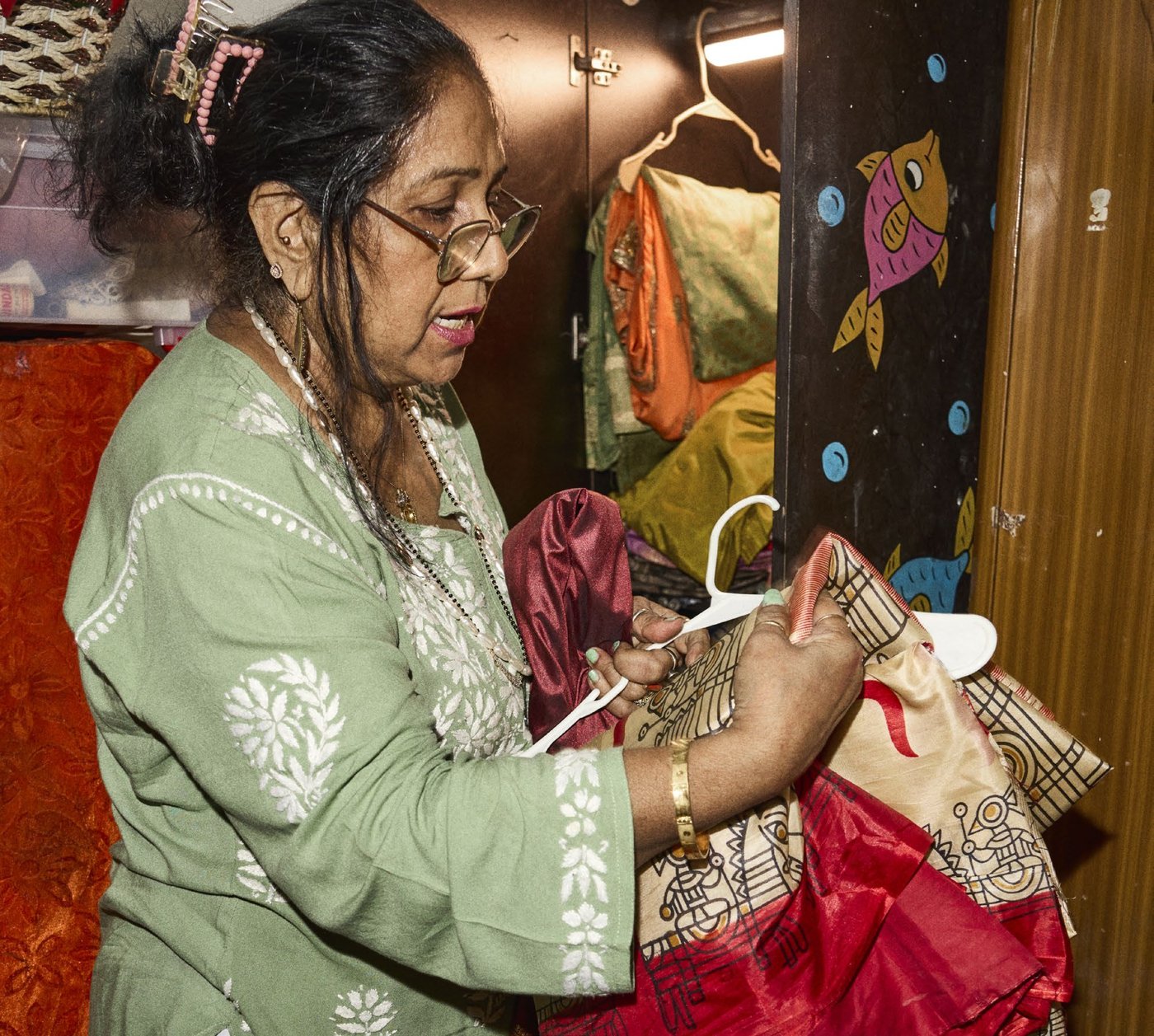 Rita looks at a sari hanging on a clothes hanger.