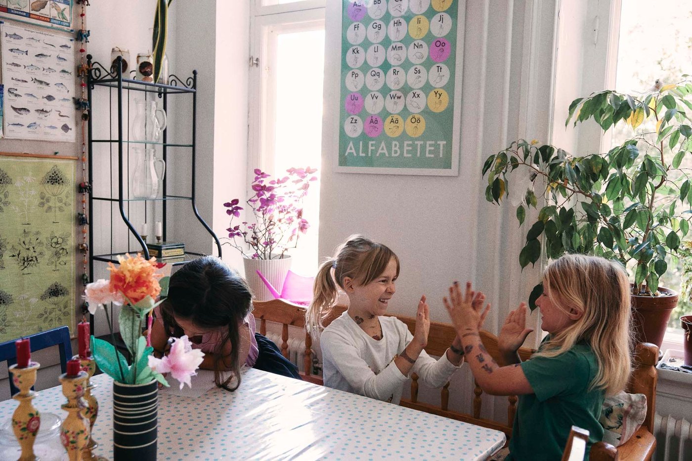 Three small children sitting and playing at a dining table.