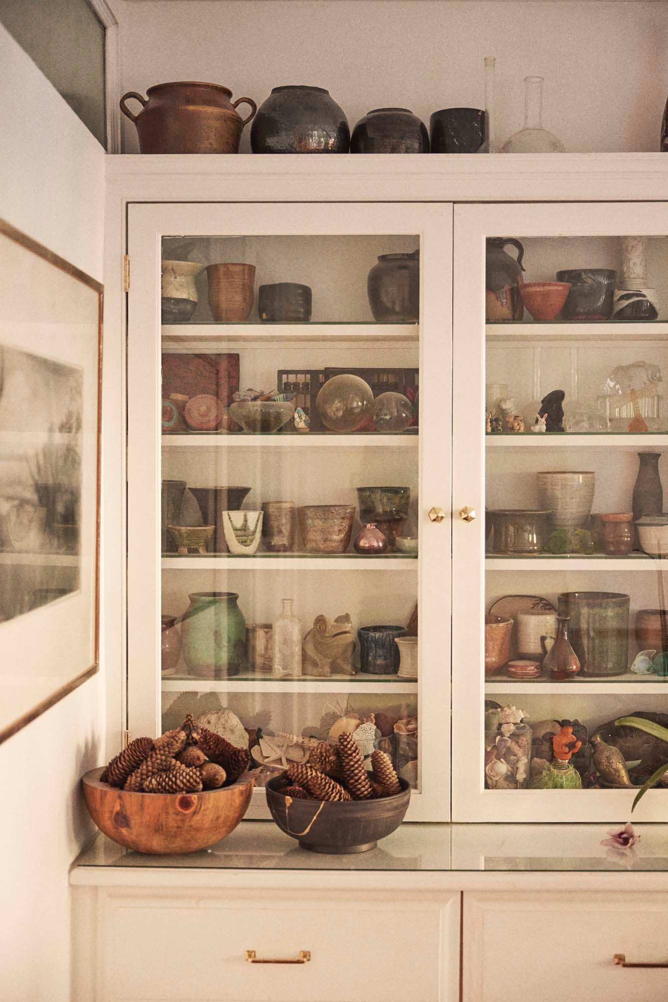 A neatly organised cabinet with glass doors.