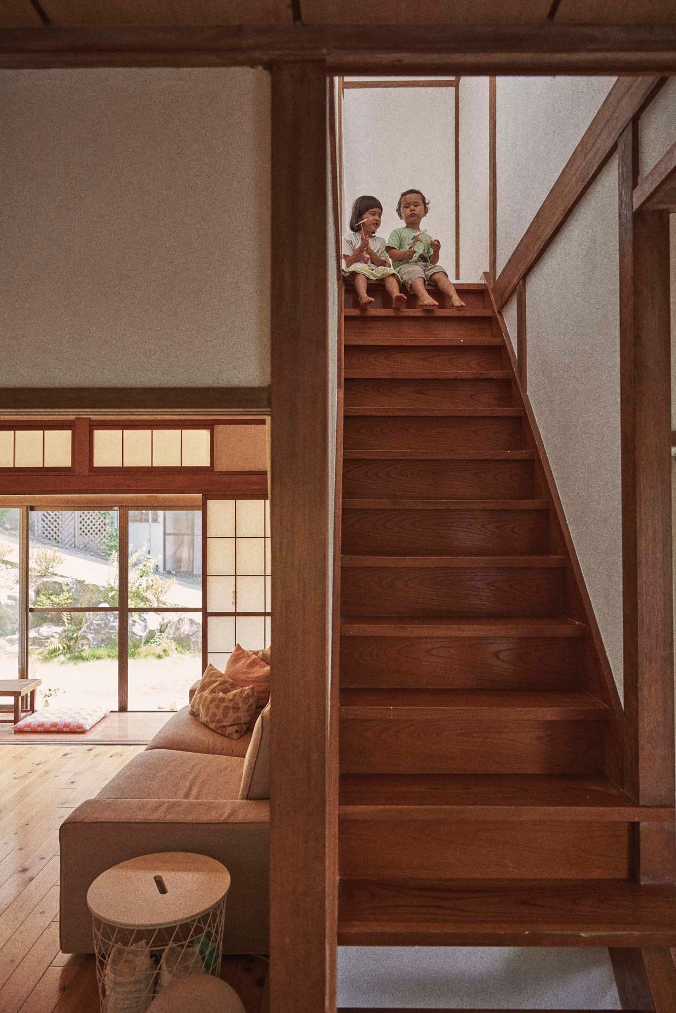 Two children sit on the top step of a staircase.