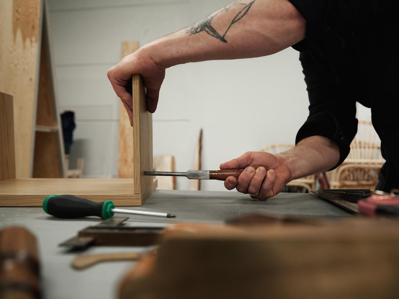 A close-up of designer Friso Wiersma's hands constructing a LÅDMAKARE storage system with tools.
