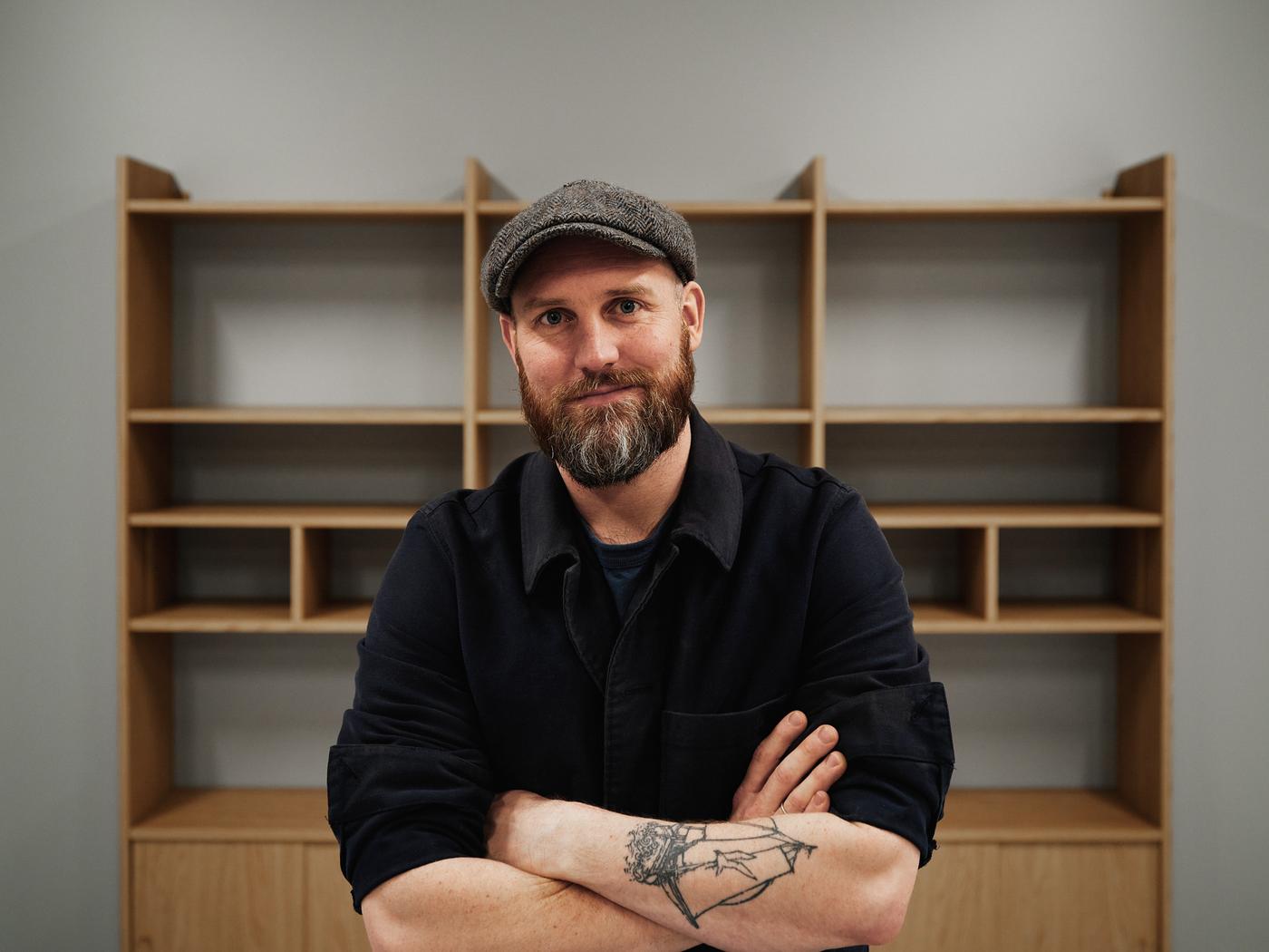 Designer Friso Wiersma stands in front of a LÅDMAKARE storage system. His arms are folded and he looks at the camera.