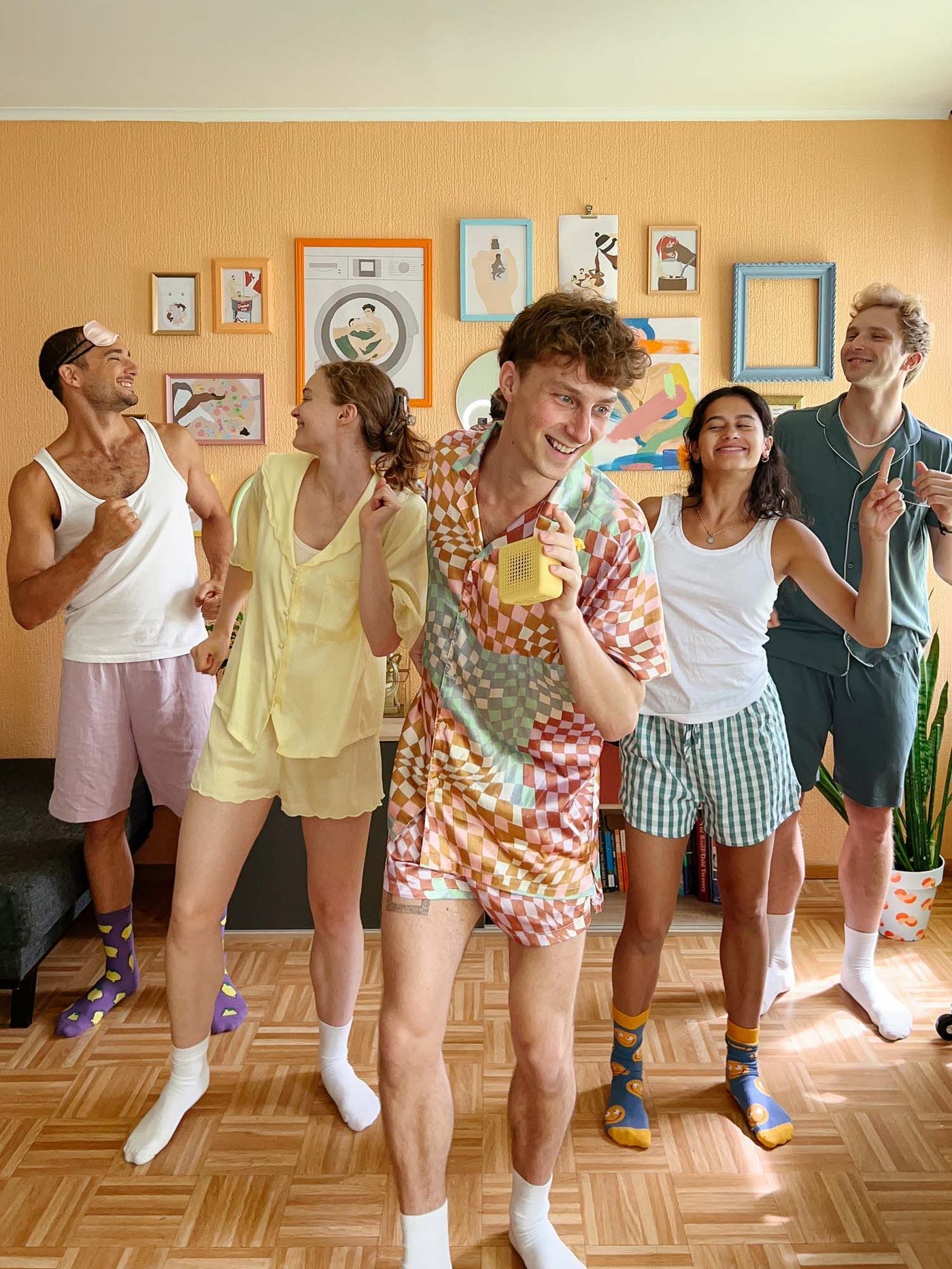 A group of five friends dance together in a colourful living room.