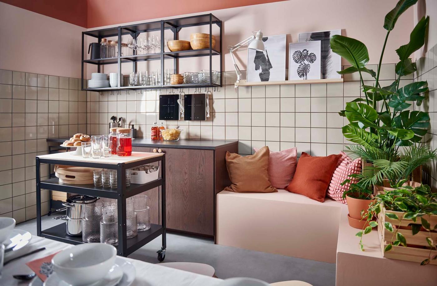 A side-by-side kitchenette and seating area, with a multi-tone palette of light pink, terracotta and gold.
