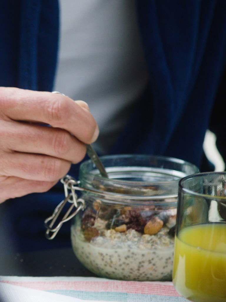 A screenshot of a hand holding a spoon, tucking into a jar of overnight oats.