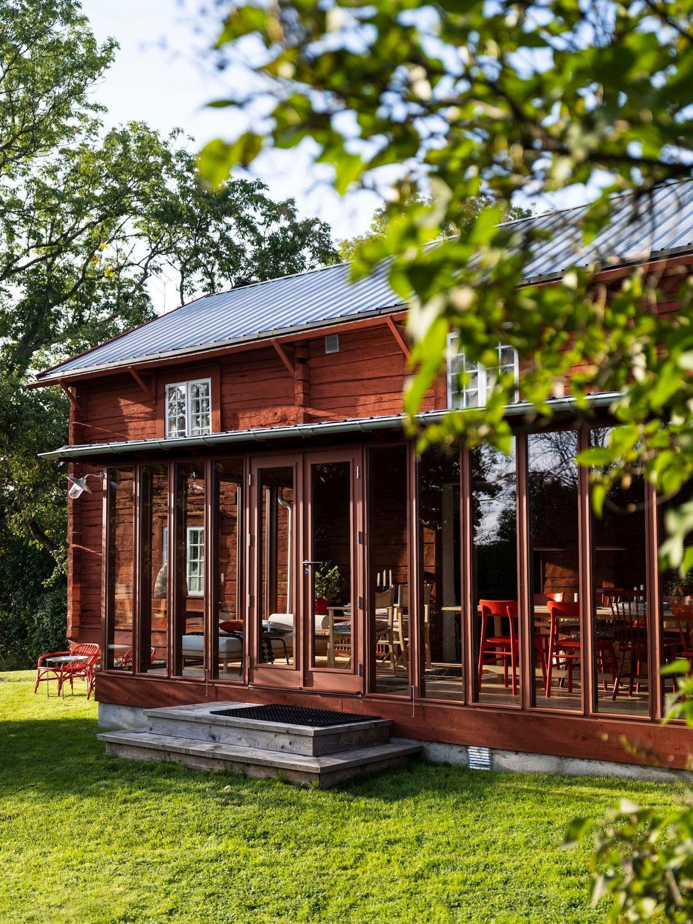 Exterior view of a red Swedish farmhouse with glassed sunroom.