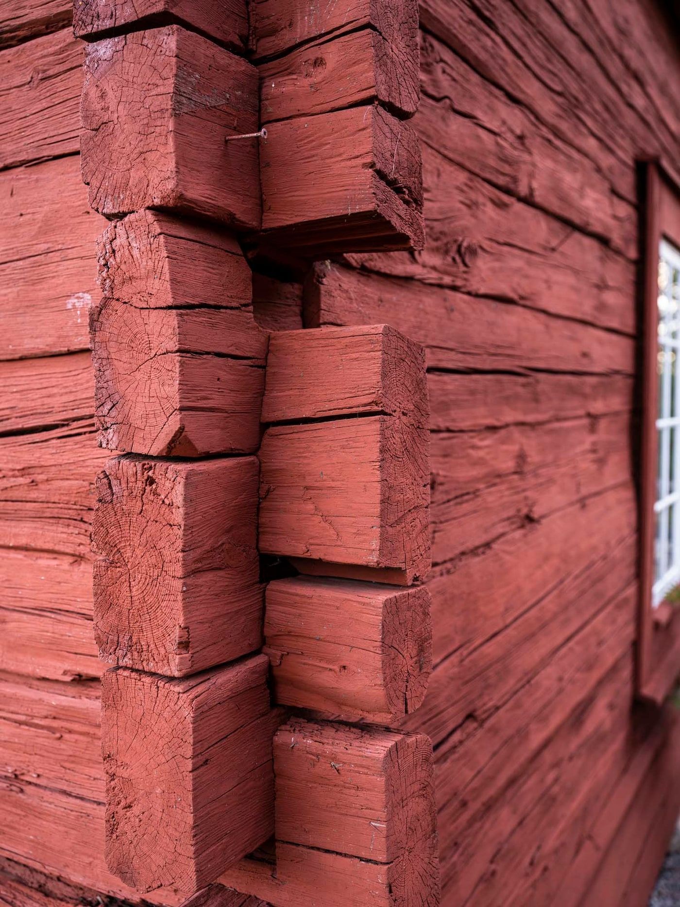 Corner of a red-painted wooden building using tradition X-joint construction.
