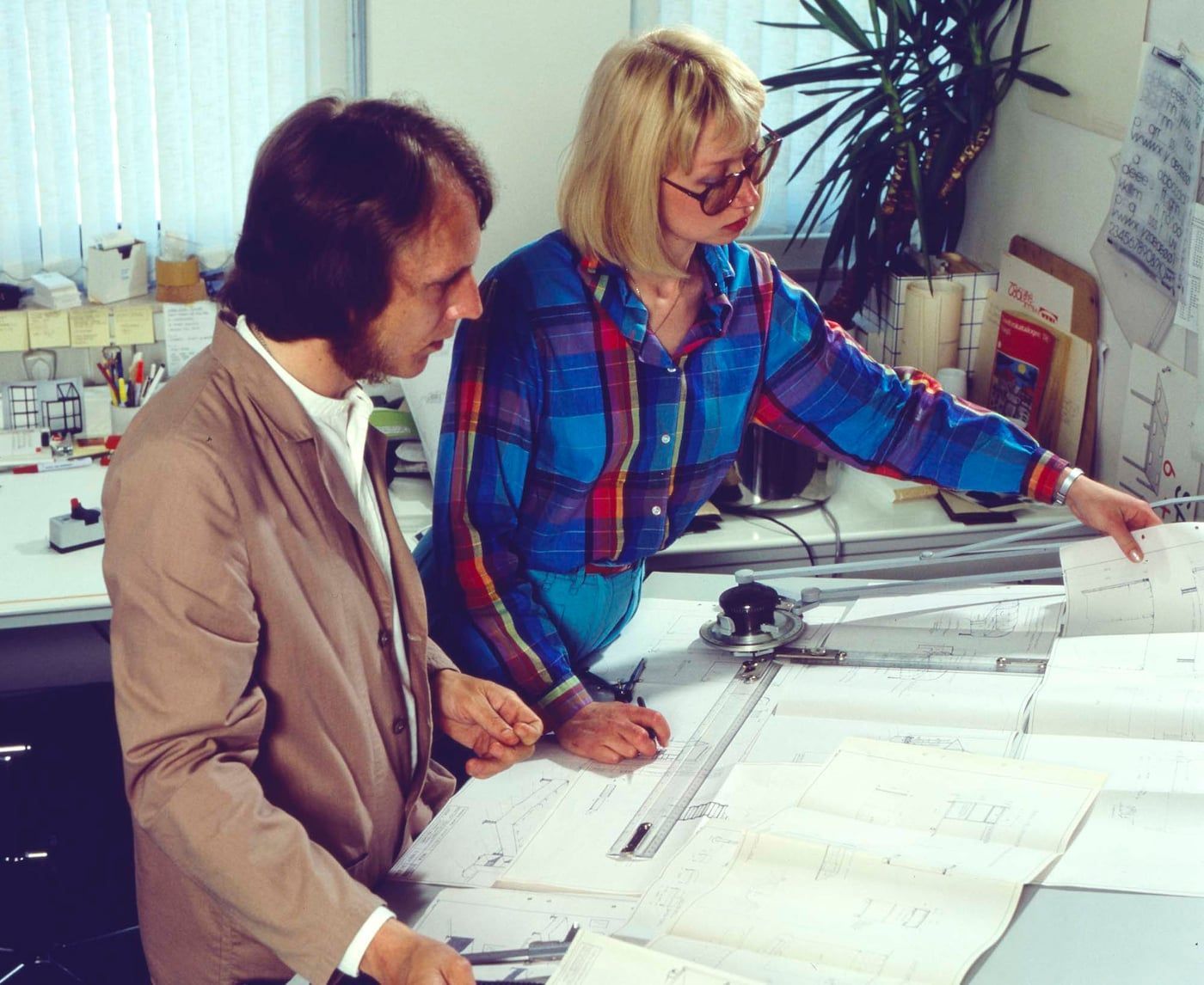 Knut Hagberg and his sister Marianne Hagberg working at their drawing board. It is full of paper.