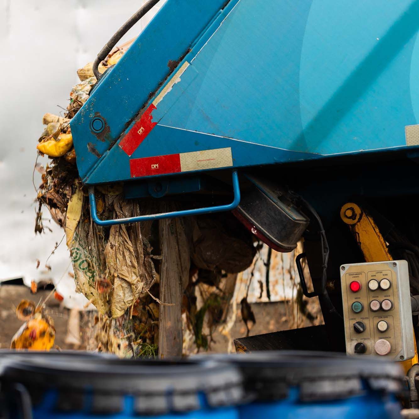The back of a blue rubbish truck filled with rubbish.