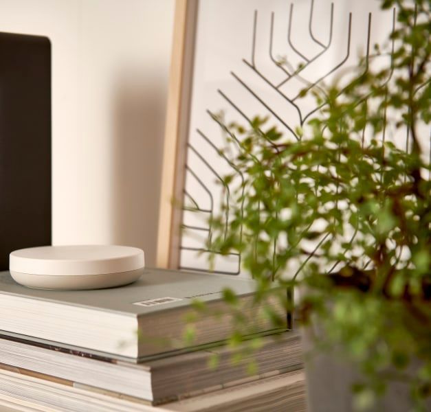 A speaker standing next to a pile of books with a white device on top.