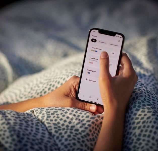A person lying in bed, holding a smartphone.