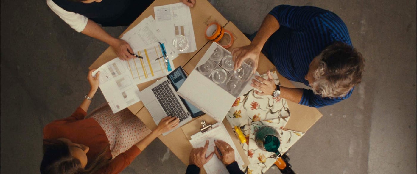 Overhead view of IKEA International Sales co-workers planning an order together in a warehouse, using a cardboard box as their table.