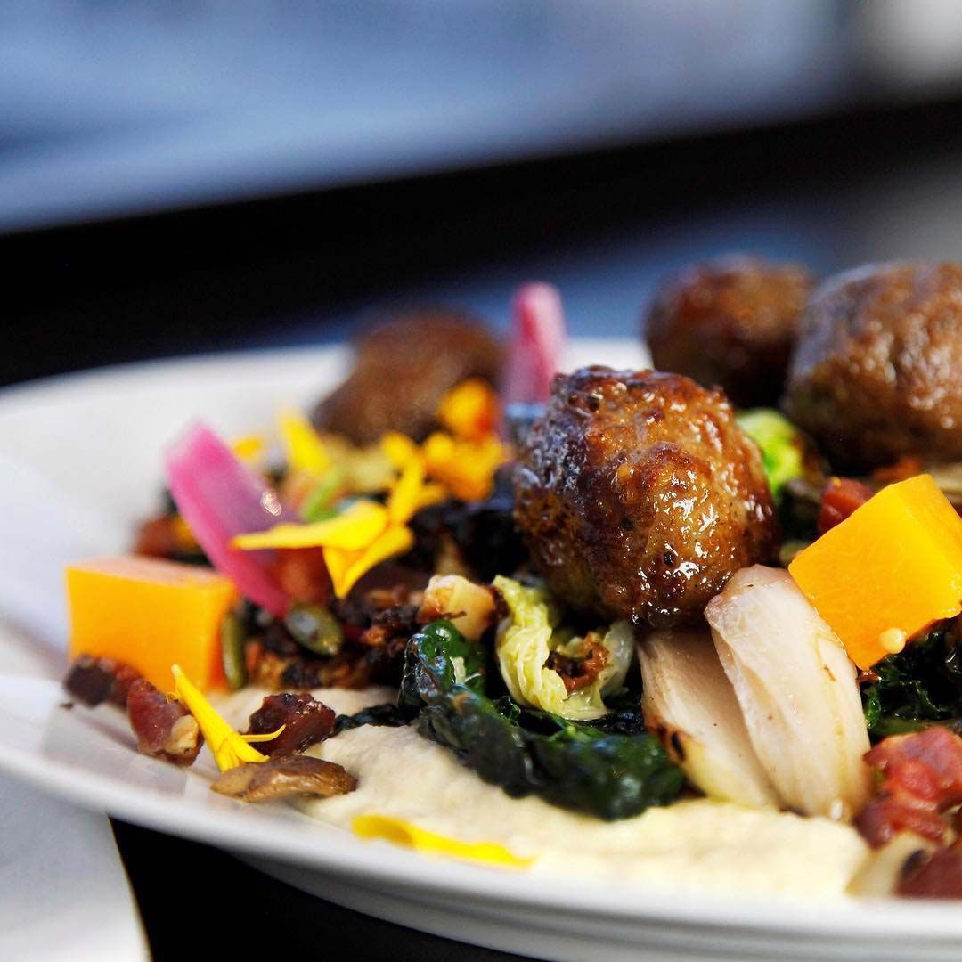 A plate of mooseballs with chanterelles, cabbage, apples and sauce on a plate.