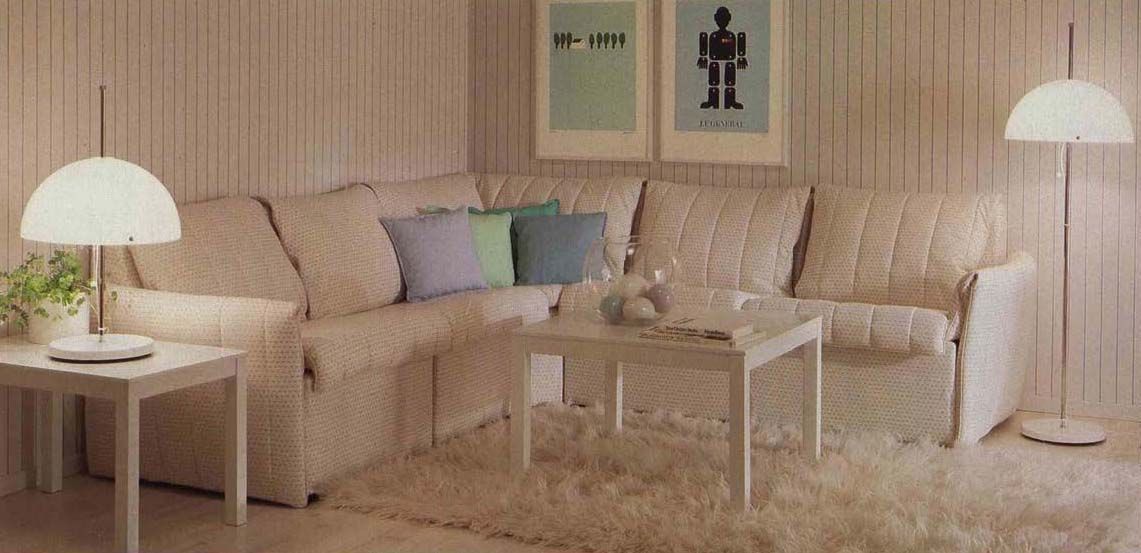 An image from the 1984 IKEA catalogue showing a white living room with a sectional sofa and two lamps.