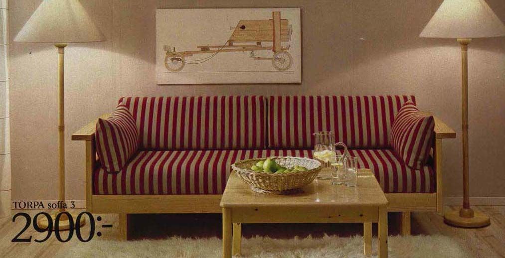 An image from the 1984 IKEA Catalogue featuring a striped sofa flanked by two floor lamps and a picture on the wall.