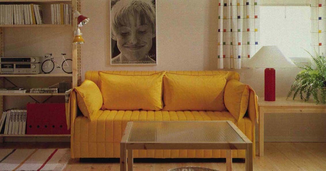 An image from the 1984 IKEA Catalogue featuring a yellow quilted sofa next to pine furniture in a living room.