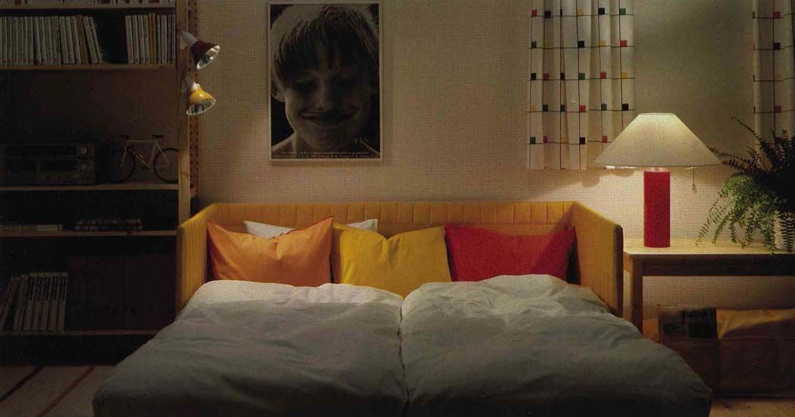 An image from the 1984 IKEA catalogue featuring a living room at night, with a yellow sofa bed.