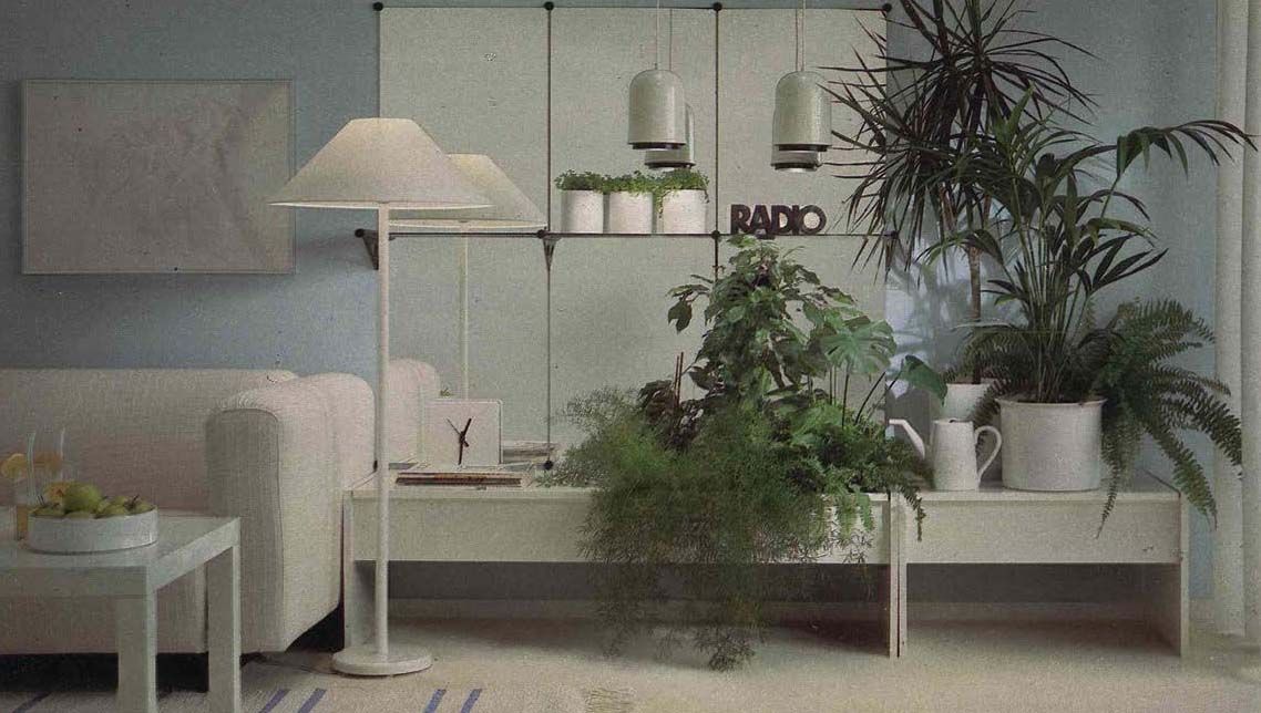 An image from the 1984 IKEA catalogue showing a living room with large mirror panels that reflect large green plants, next to a sofa.
