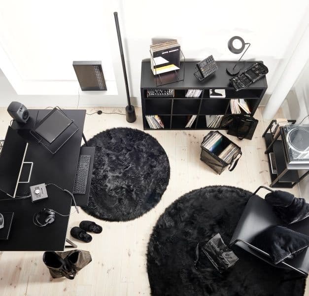 A room furnished with a black desk, a black KALLAX shelf, black carpets, and a black chair.