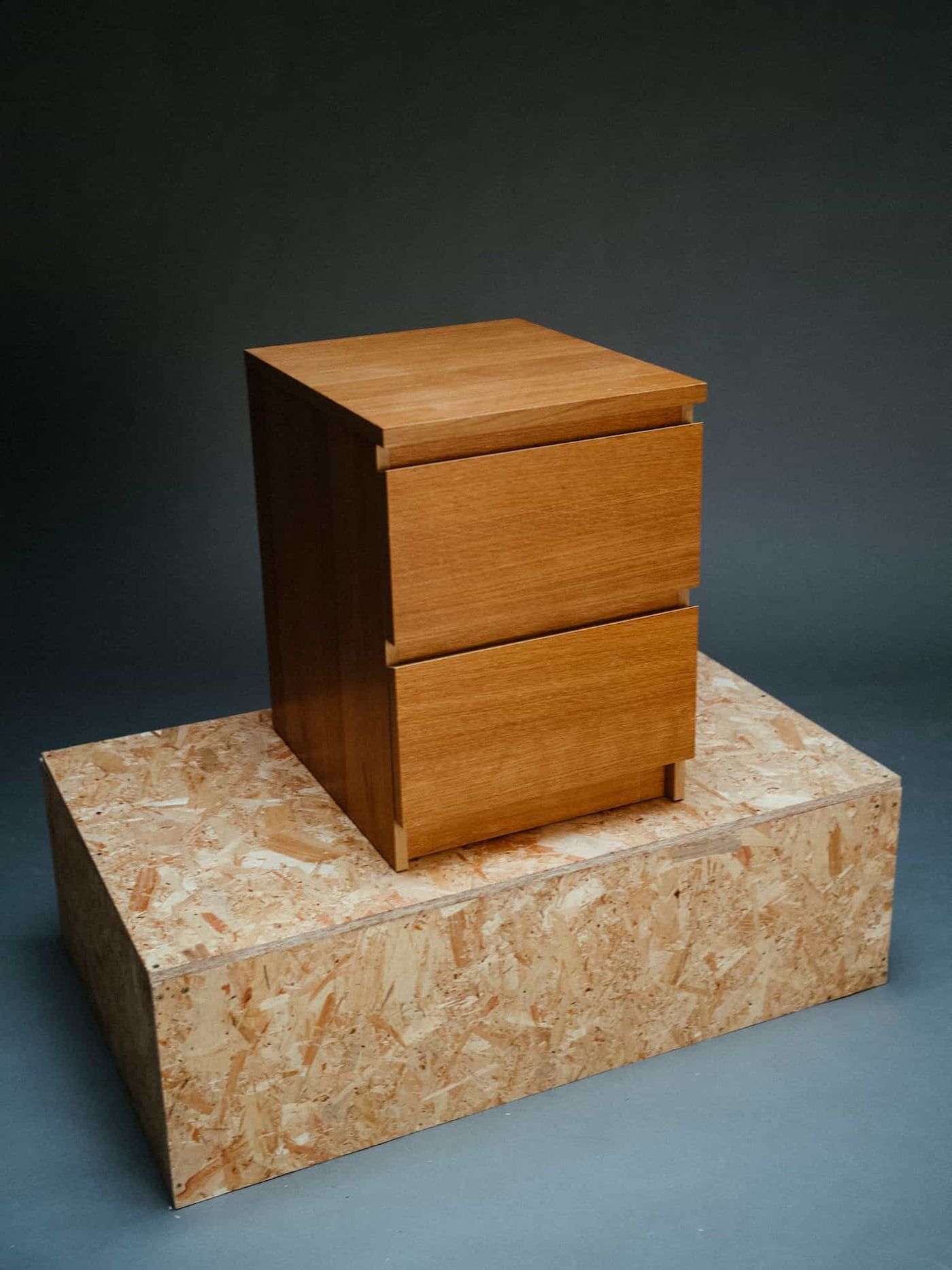 A restored chest of drawers displayed on a chipboard podium.