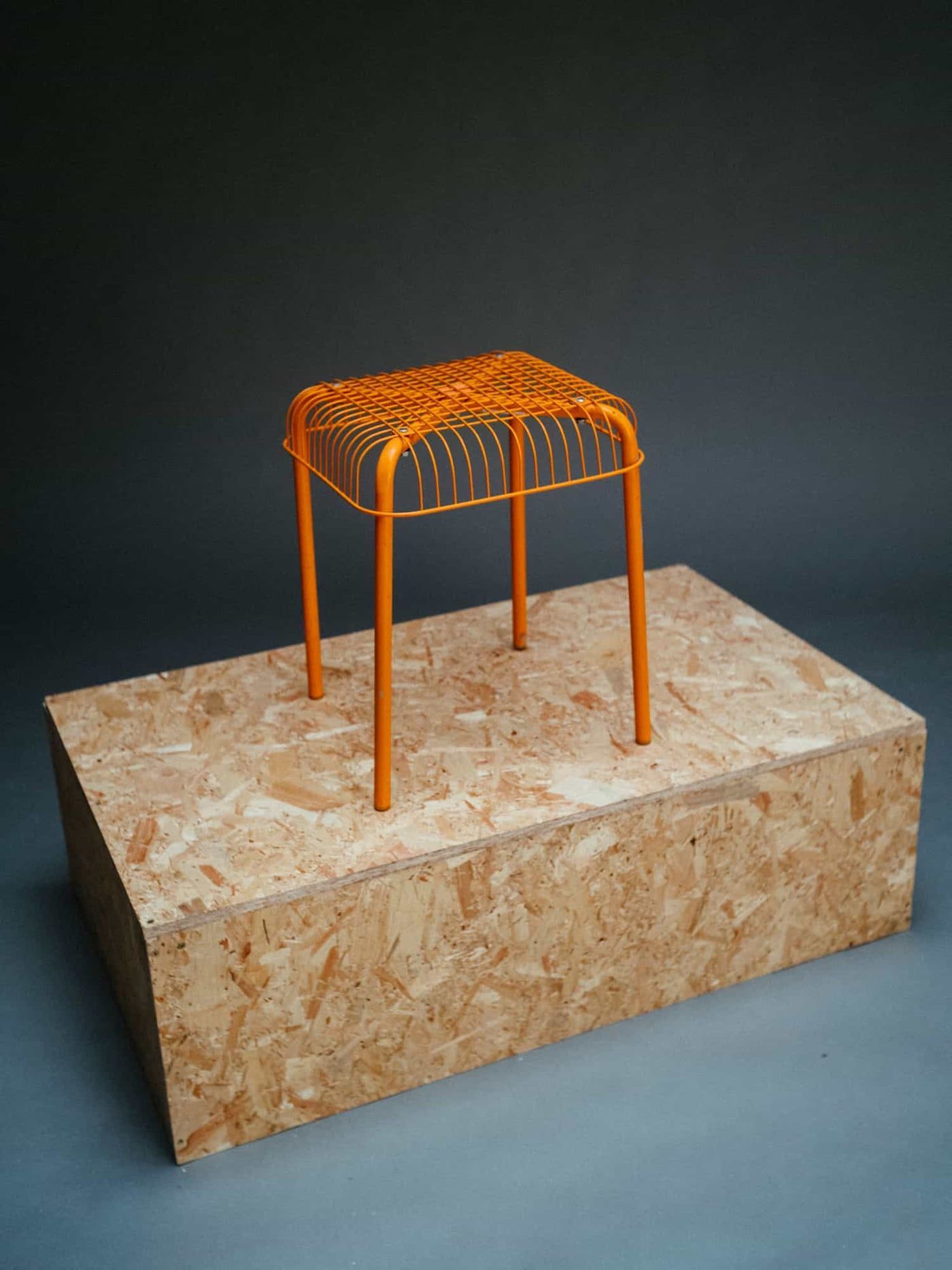 Restored orange stool displayed on a podium.