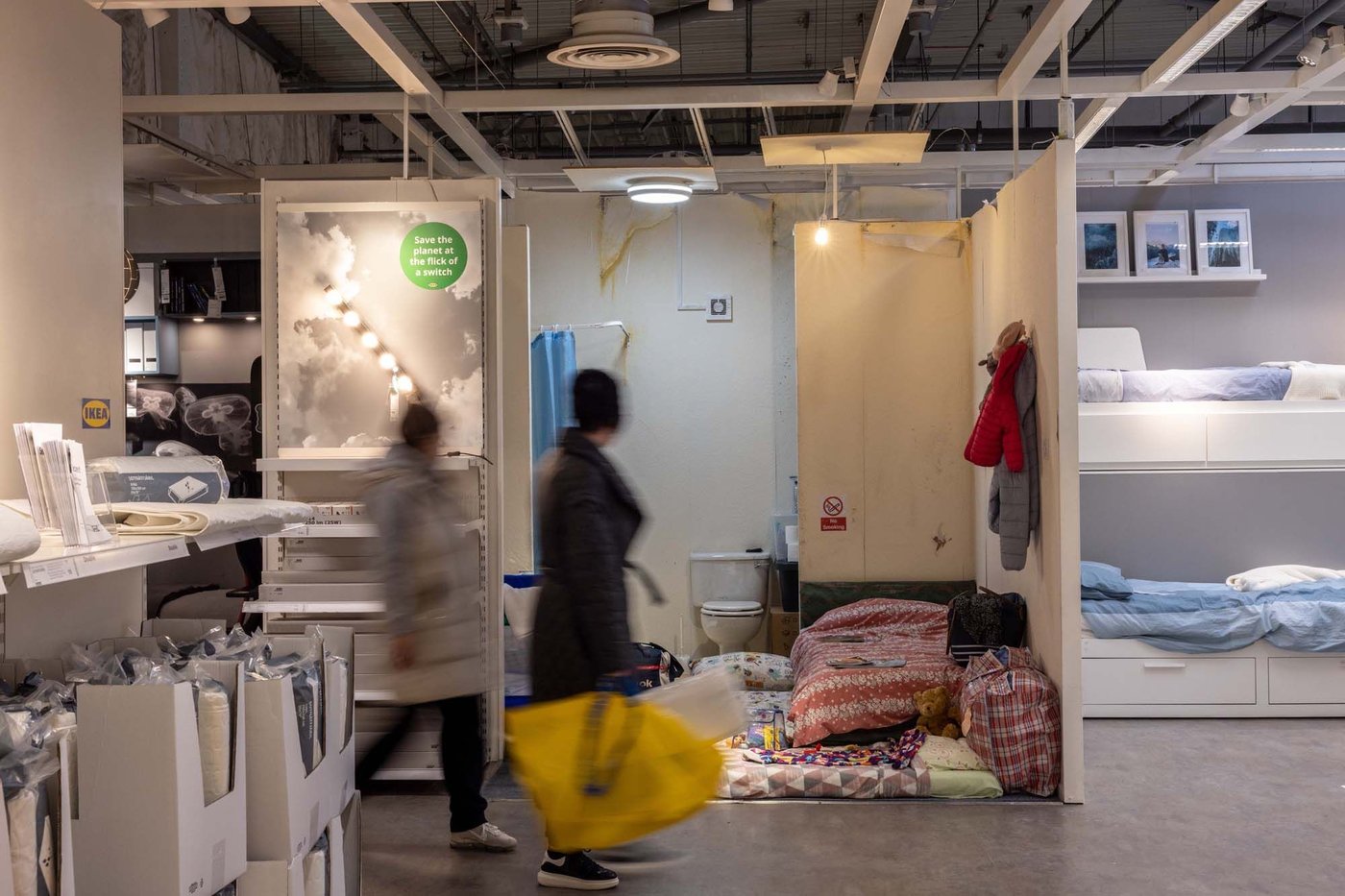 Customers walk past one of the IKEA x Shelter roomsets at IKEA Birmingham.