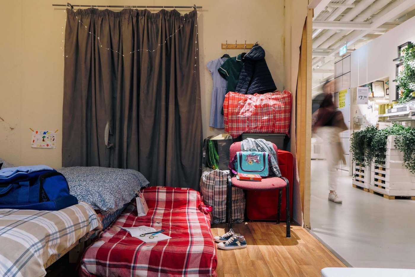 Bags full of clothes and belonging are piled in the corner of a real-life roomset at the IKEA Hammersmith store.