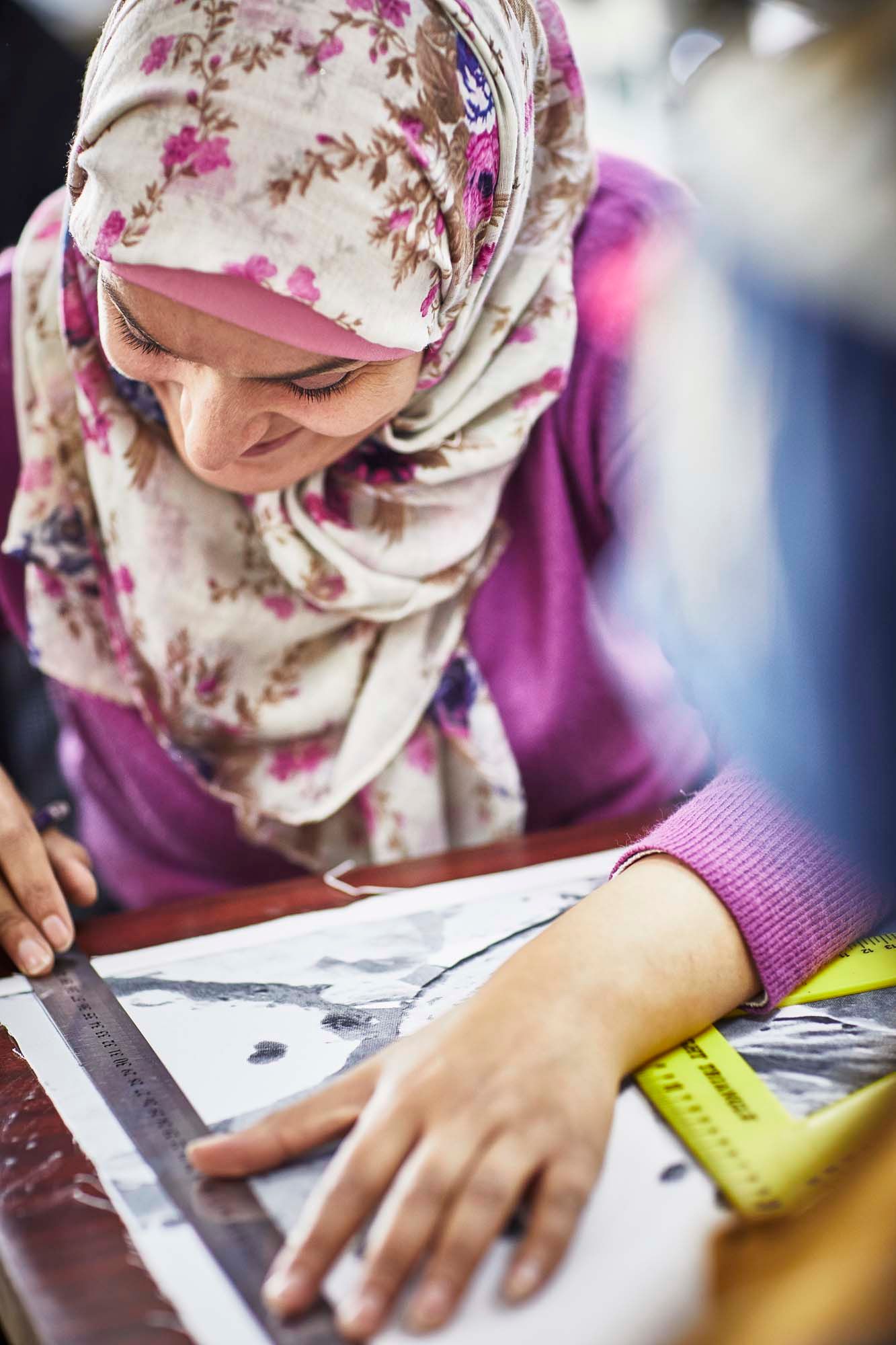 A woman in a floral hijab smiles as she designs.