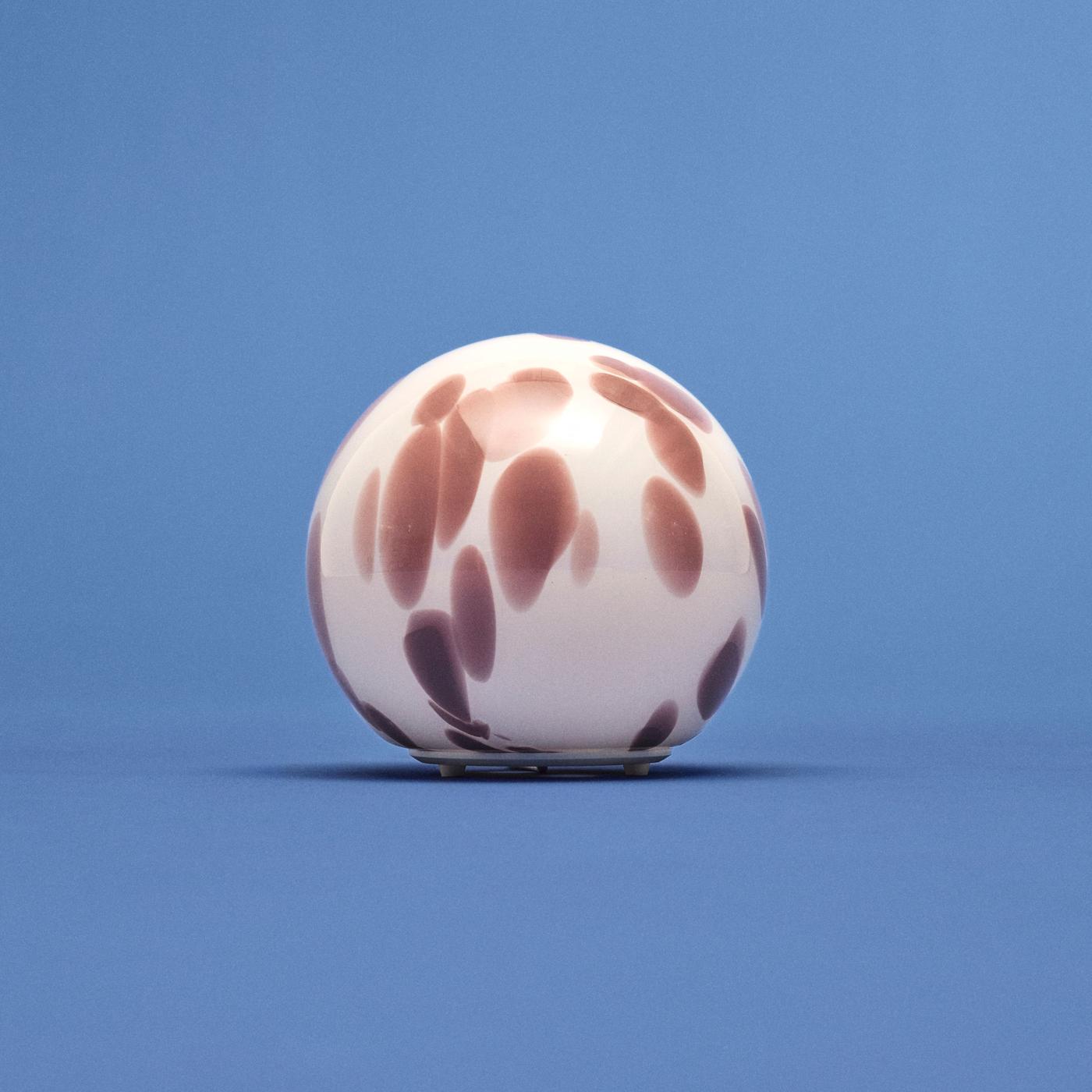Spherical FADO lamp with patterned spots in varying intensity, standing against a blue background.