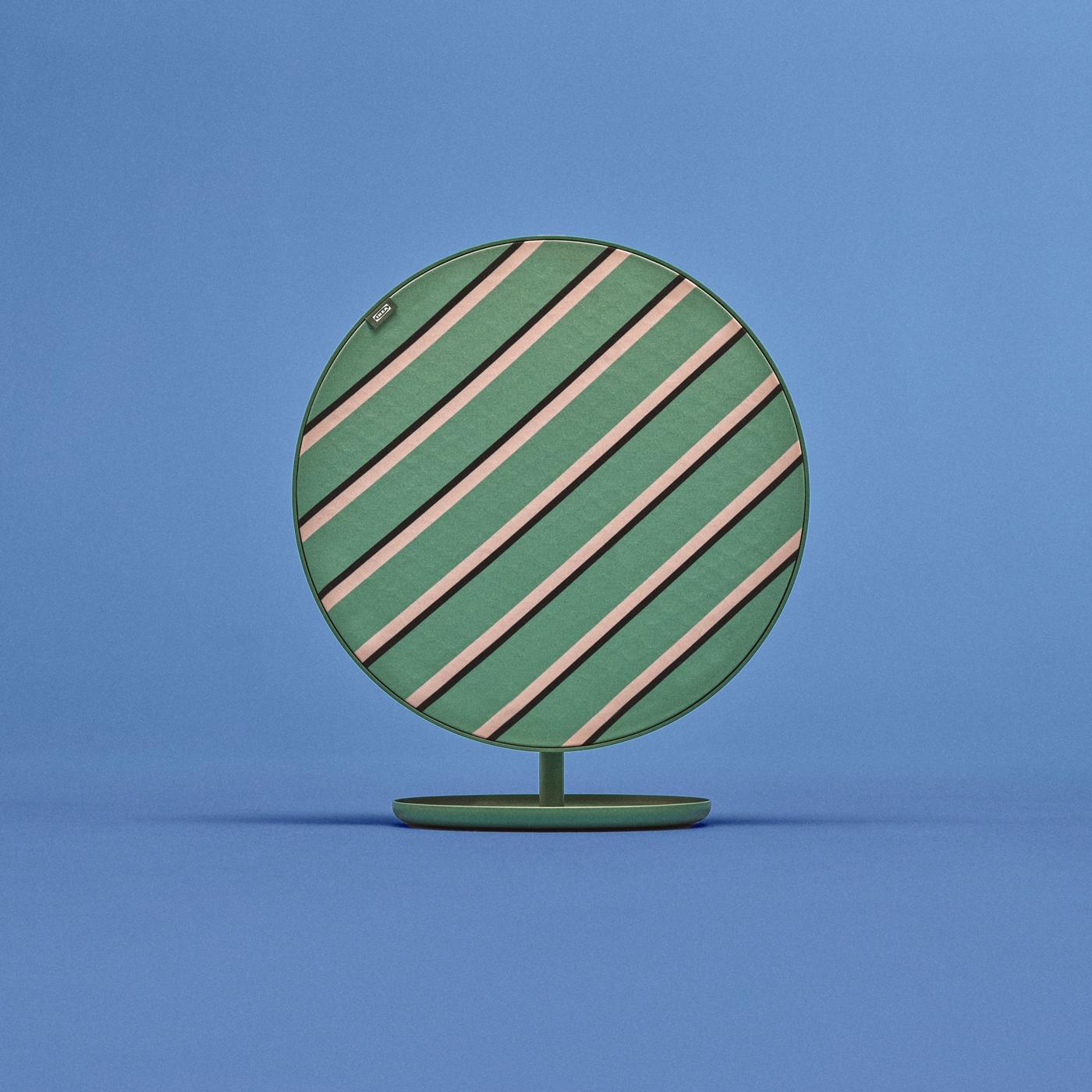 Medium-sized round SOLSKYDD speaker with green, beige, and black cross-stripe pattern on matching green stand, set against a blue background.