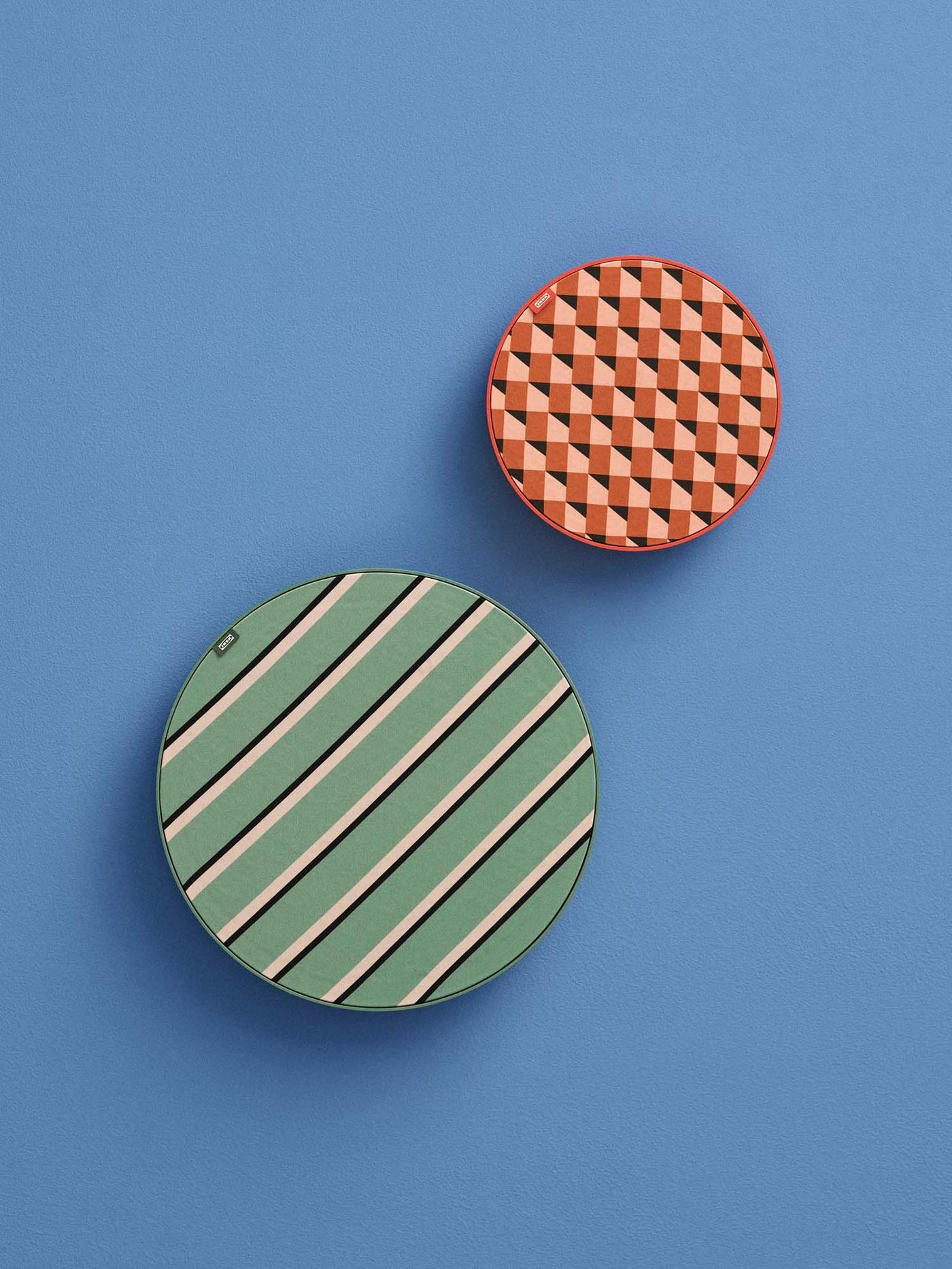 Two colourful, patterned SOLSKYDD speakers hanging on a blue wall.ing