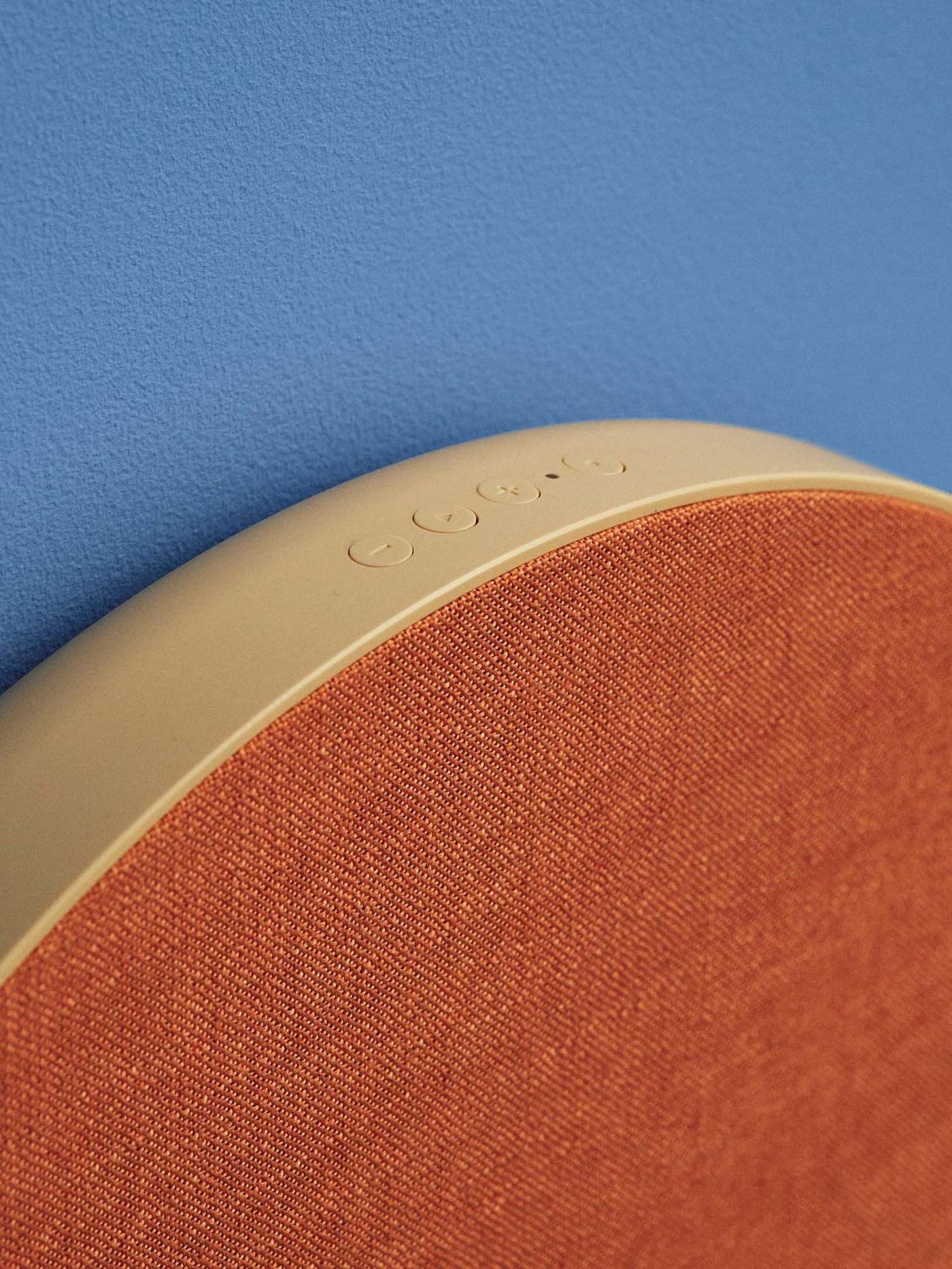 The edge of a yellow and orange SOLSKYDD speaker against a blue background..