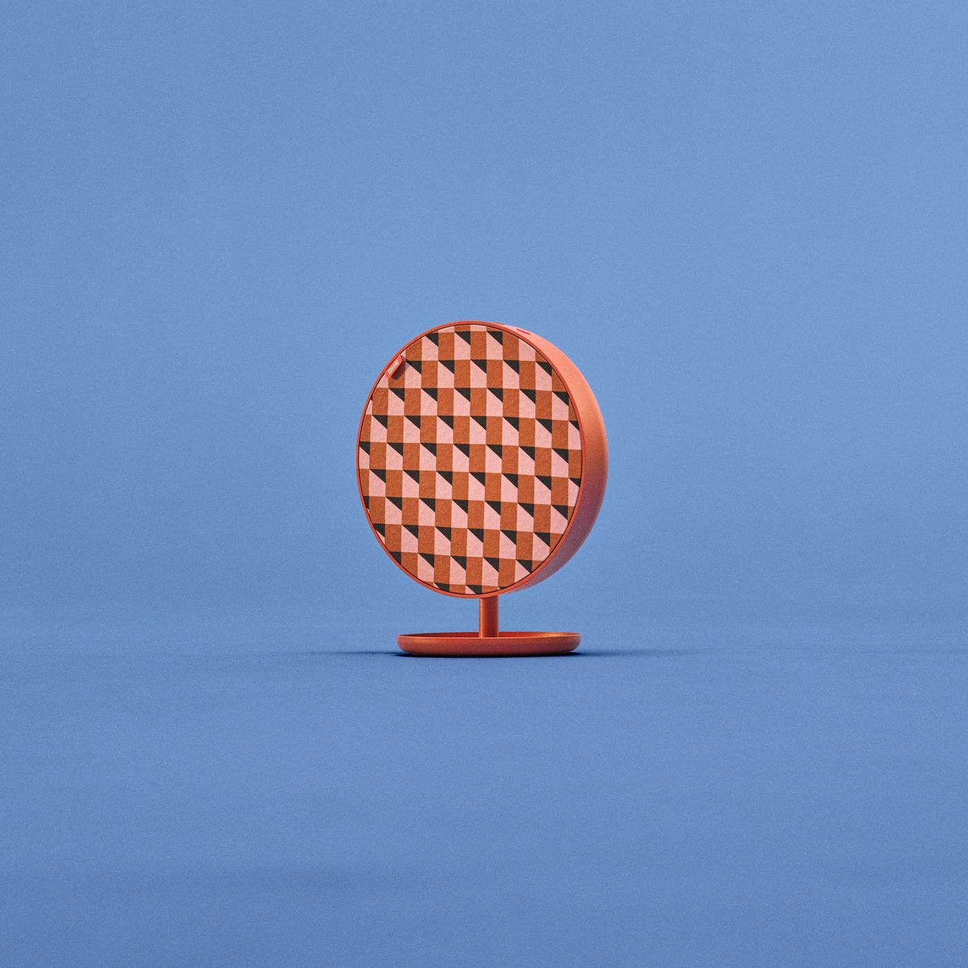Round SOLSKYDD speaker with red-pink zigzag pattern on red stand, viewed slightly from the side, set against a blue background.