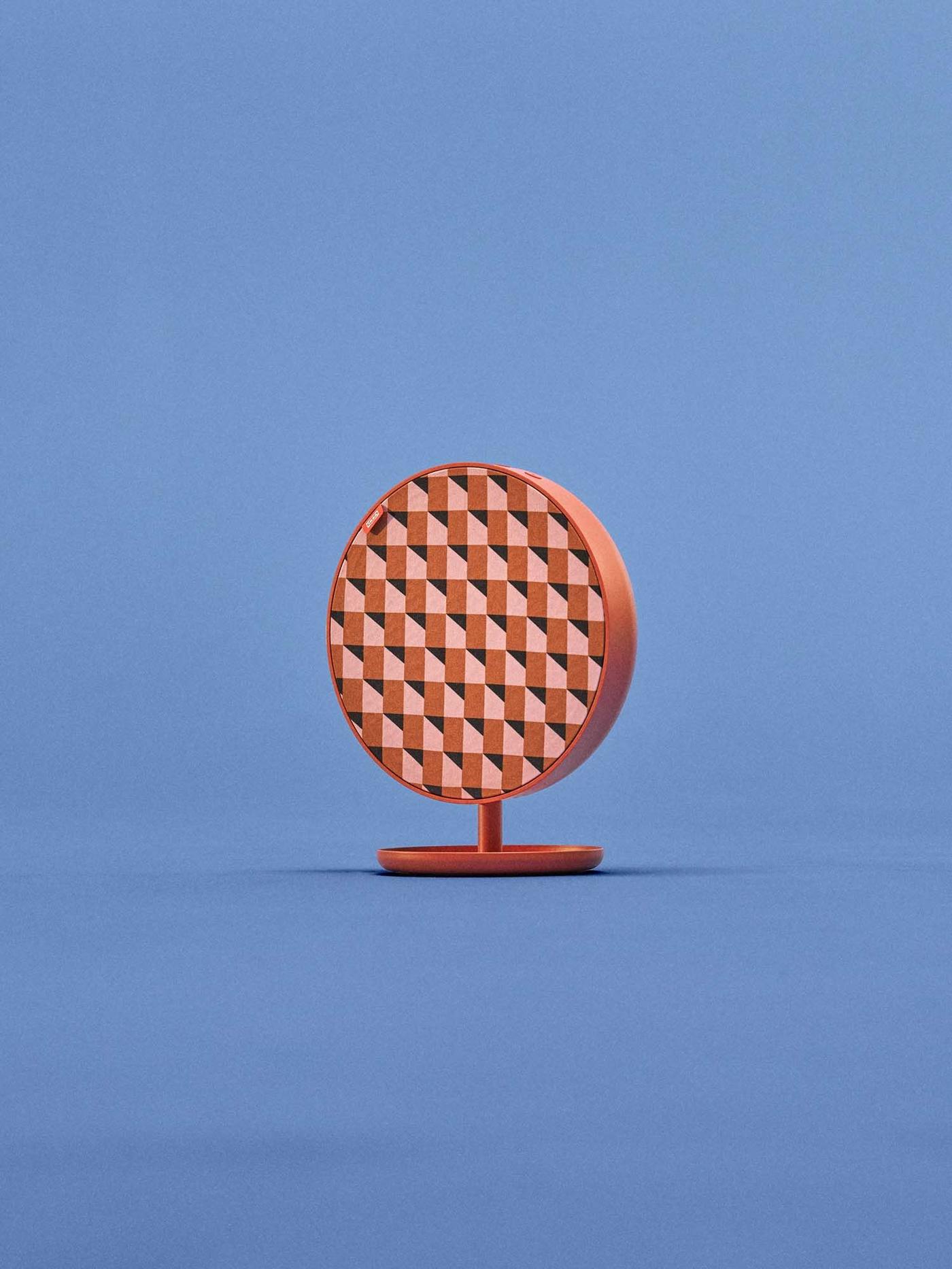 A red-orange patterned SOLSKYDD speaker with a stand, against a blue backdrop.