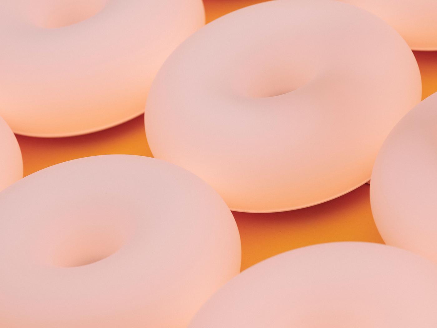 A close-up of peach-coloured donut-shaped lamps, tightly arranged on a dark yellow surface.