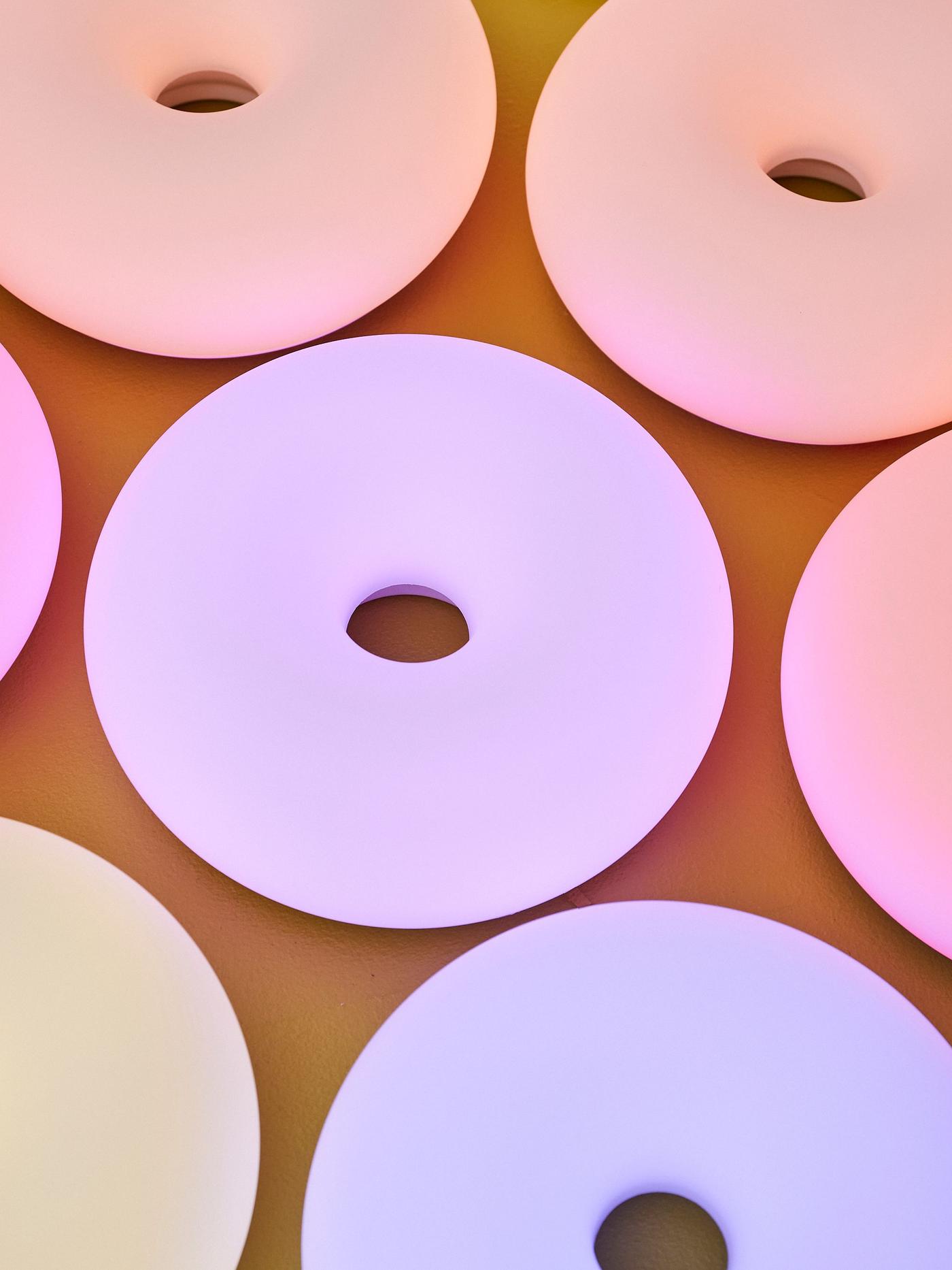 Glowing donut-shaped lamps in various colours — arranged closely together.