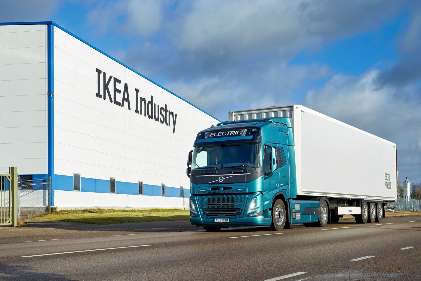 A blue and white truck drives past an IKEA Industry facility.
