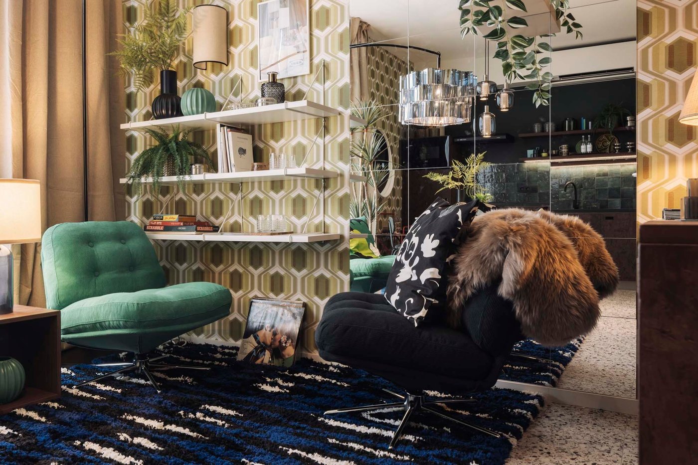 A living area with plants and trinkets on white shelves on a wall with a green and a black DYVLINGE swivel armchair below.