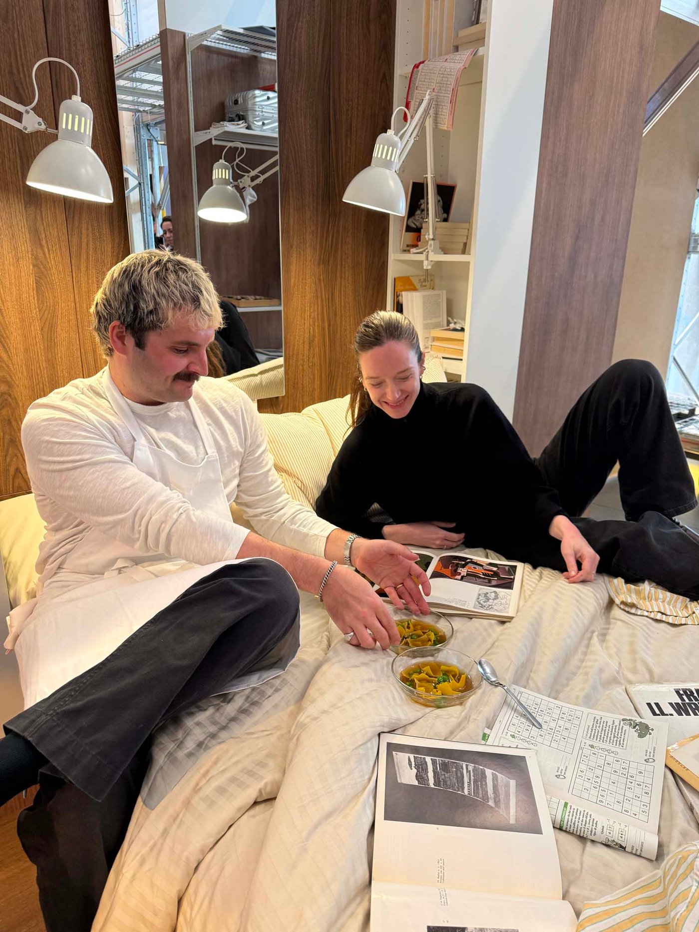 Charlotte and Ben sit on a cosy bed with two bowls of food.
