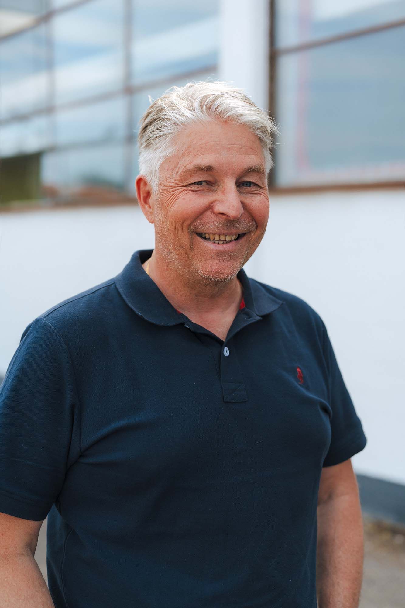 IKEA co-worker Roger Nilsson looks at the camera and smiles. He is standing in front of an industrial building.