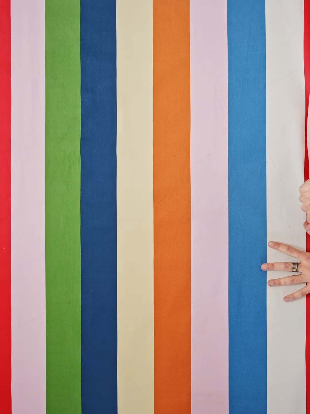 A still from a video showing a pair of hands on a piece of striped fabric.