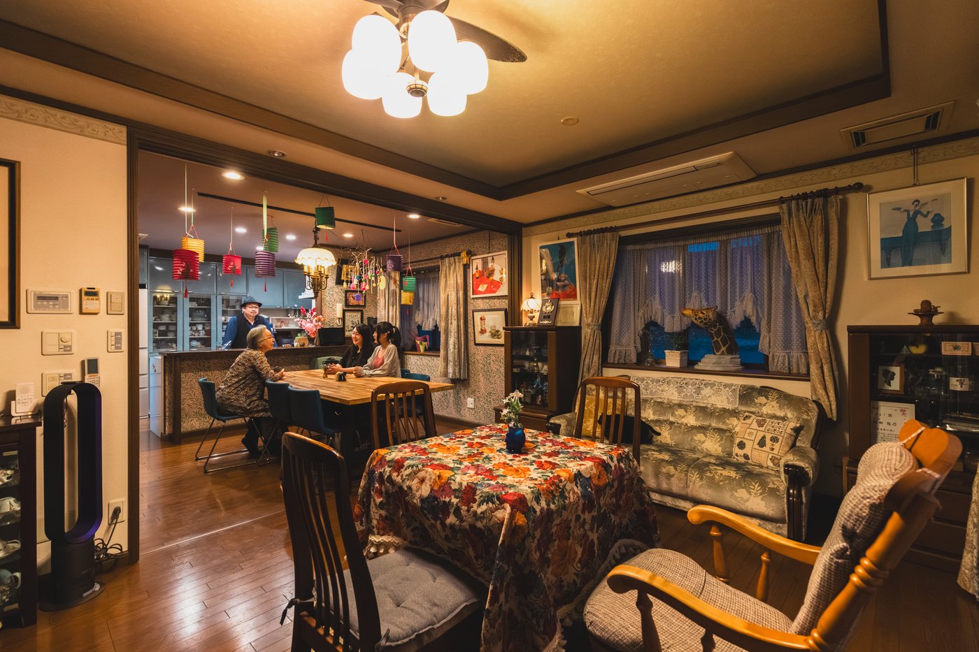 a multi-generation family sit in the dining area of a restaurant with floral tablecloths.