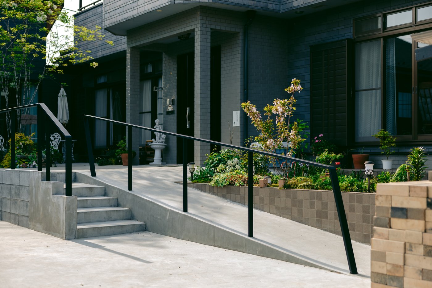 Concrete stairs and a sloped path in front of a dark grey building.