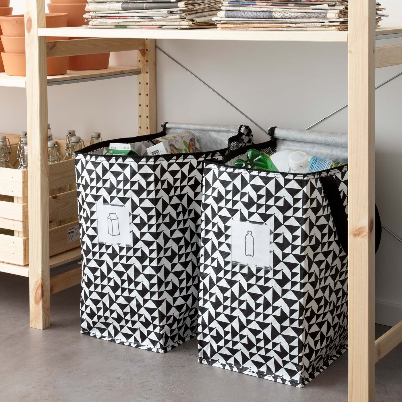 Two black and white KNALLA storage bags together below wooden IVAR shelves.