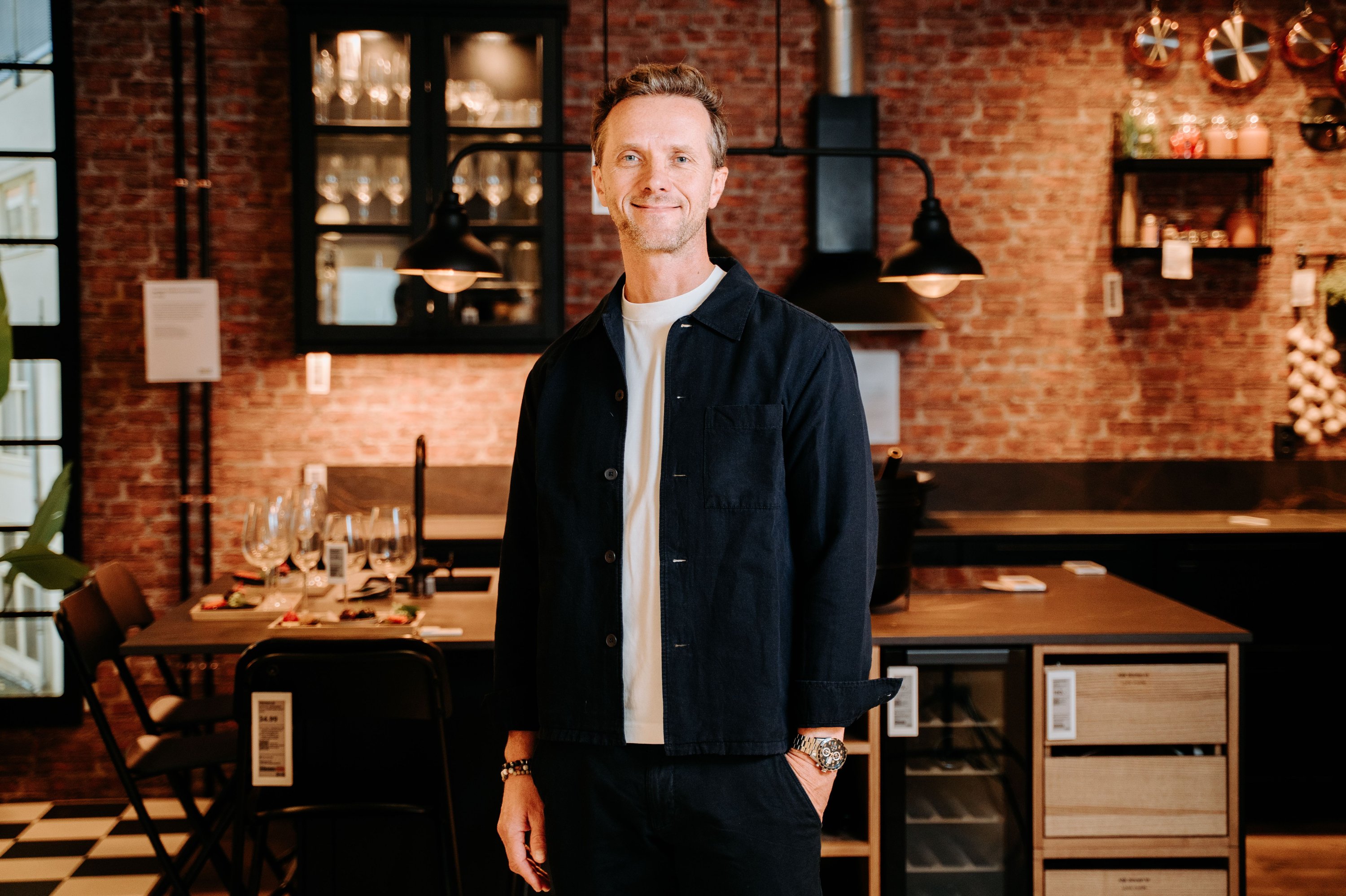 Inter IKEA Group CEO Kuba Jankowski stands in front of a warmly-lit IKEA kitchen, smiling.